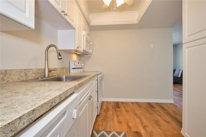 Kitchen featuring white appliances, white cabinetry and tray ceiling.
