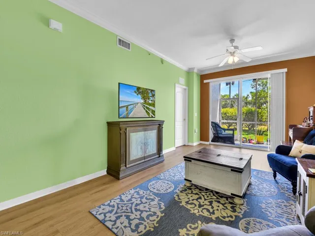 Living room with baseboards, ornamental molding, and wood finished floors