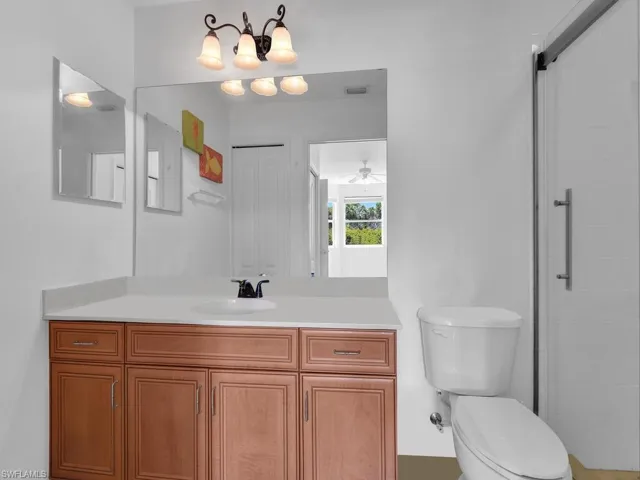 Bathroom featuring ceiling fan, visible vents, a tile shower, vanity, and toilet