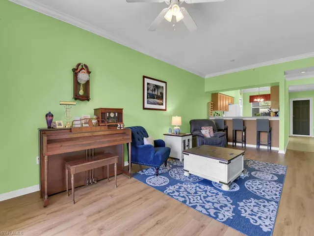Living room with crown molding, baseboards, a ceiling fan, and wood finished floors