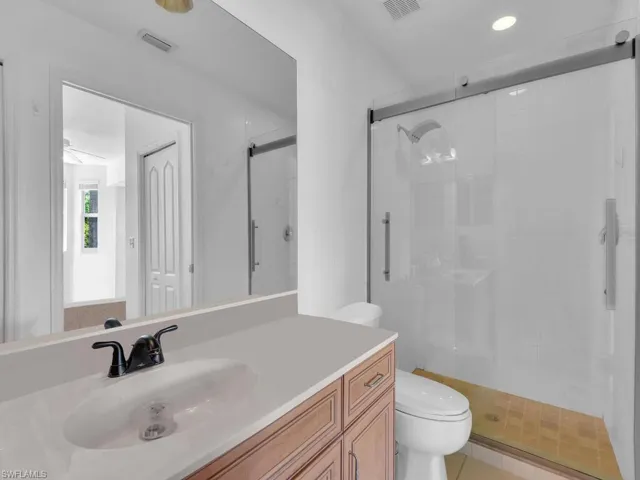 Full bathroom with vanity, a shower stall, toilet, and visible vents