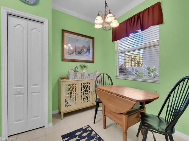 Dining room featuring baseboards, ornamental molding, light tile patterned floors, and a notable chandelier