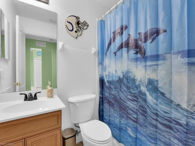 Bathroom featuring vanity, a shower with shower curtain, toilet, and visible vents