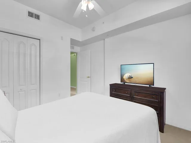 Bedroom with a ceiling fan, a closet, light colored carpet, and visible vents