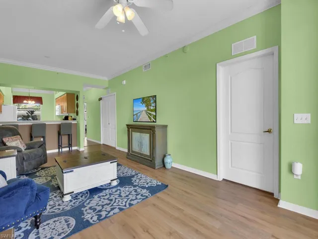 Living area featuring visible vents, baseboards, ceiling fan, and wood finished floors