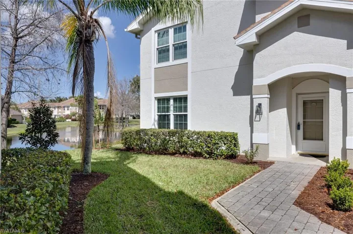 View of exterior entry featuring a yard, stucco siding, and a water view