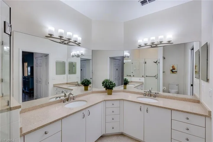 Bathroom featuring a shower stall and double vanity