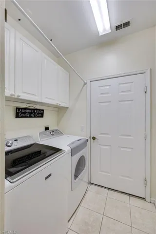 Laundry area featuring cabinet space, light tile patterned floors, and washer and clothes dryer