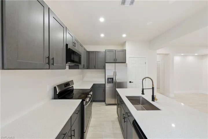 Kitchen featuring stainless steel appliances, recessed lighting, and light stone countertops