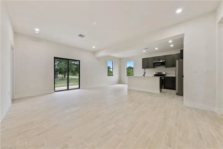 Unfurnished living room featuring recessed lighting, healthy amount of natural light, light wood-style floors, and beam ceiling