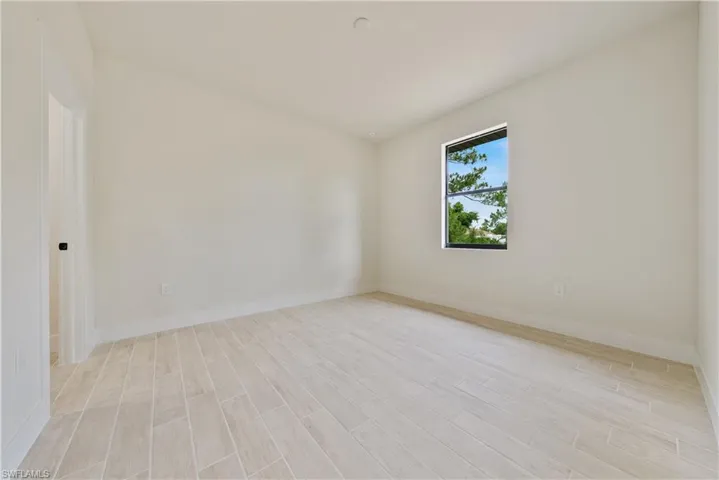 Empty room featuring baseboards and light wood-type flooring