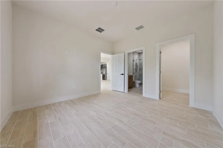 Unfurnished bedroom with wood tiled floors and ensuite bath