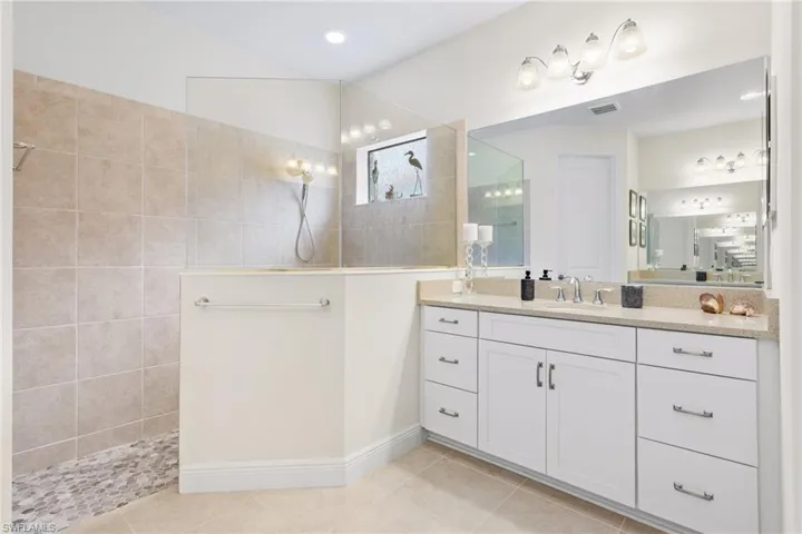 Bathroom with tiled shower, vanity, and tile patterned flooring