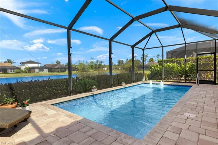 View of pool with a water view and glass enclosure