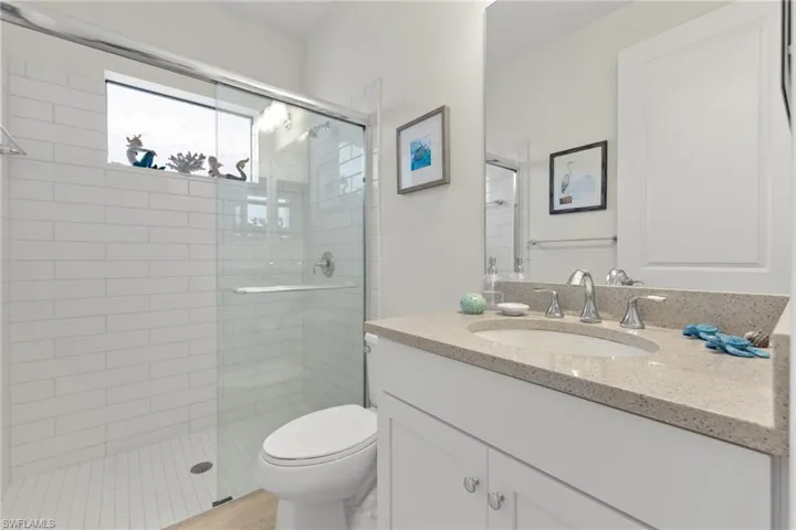 Bathroom featuring vanity, toilet, and an enclosed shower