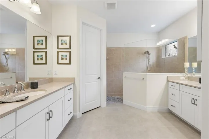 Bathroom with tiled shower, tile patterned flooring, and vanity