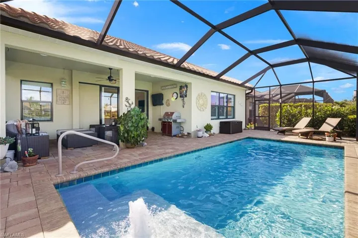 View of swimming pool with area for grilling, ceiling fan, a lanai, and a patio area