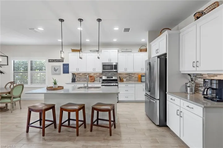 Kitchen featuring a breakfast bar, stainless steel appliances, sink, decorative backsplash, and white cabinetry
