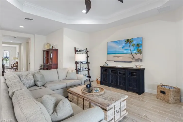 Living room featuring crown molding, a raised ceiling, and light hardwood / wood-style flooring