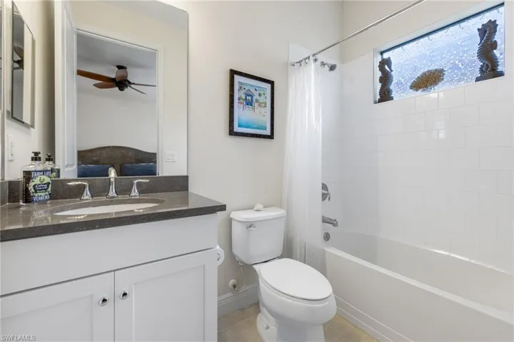 Full bathroom featuring vanity, tile patterned flooring, toilet, shower / bath combo with shower curtain, and ceiling fan