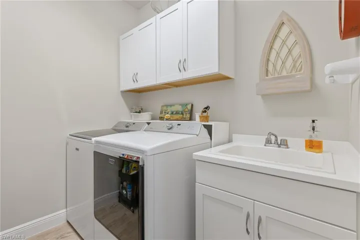 Laundry room with cabinets, independent washer and dryer, sink, and light hardwood / wood-style floors