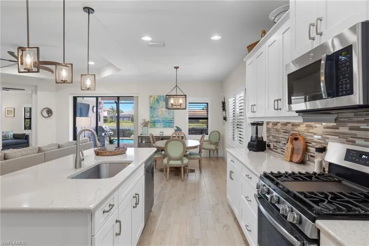 Kitchen with appliances with stainless steel finishes, a wealth of natural light, sink, and hanging light fixtures