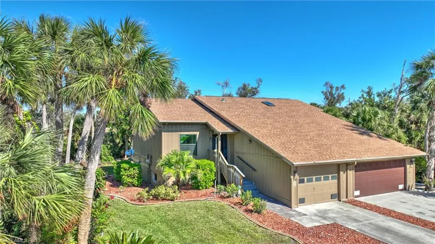 View of front of property featuring concrete driveway, a shingled roof, a front lawn, and a garage