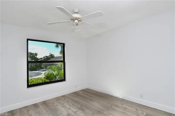 Unfurnished room featuring a textured ceiling, light wood-type flooring, and a ceiling fan