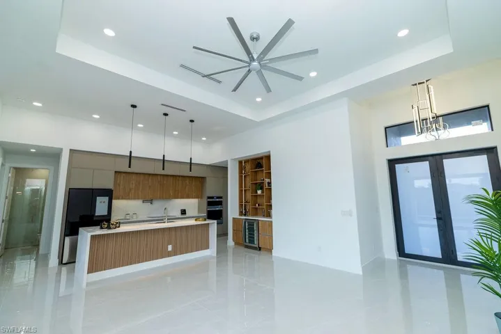 Kitchen with a spacious island, wine cooler, sink, a raised ceiling, and pendant lighting