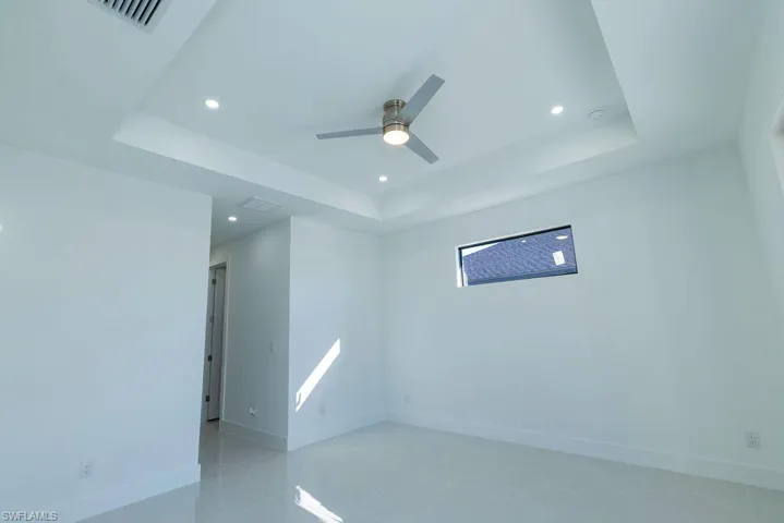 Empty room with ceiling fan and a tray ceiling