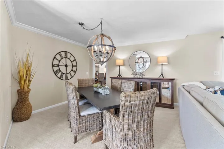 Dining area with an inviting chandelier, light carpet, and ornamental molding
