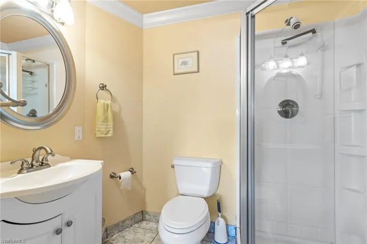 Bathroom with an enclosed shower, tile patterned floors, toilet, vanity, and ornamental molding