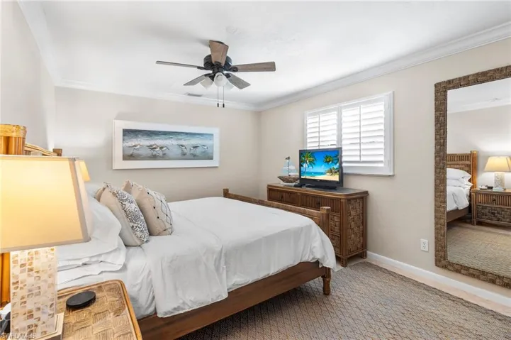 Carpeted bedroom featuring ceiling fan and crown molding
