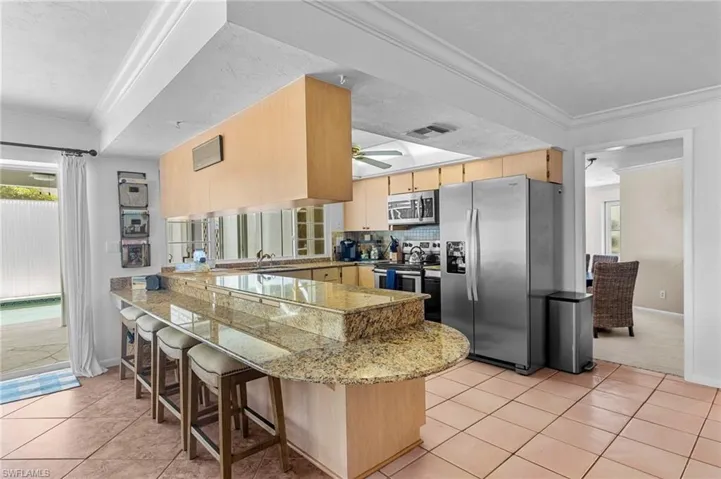 Kitchen featuring appliances with stainless steel finishes, kitchen peninsula, a breakfast bar area, and light tile patterned floors