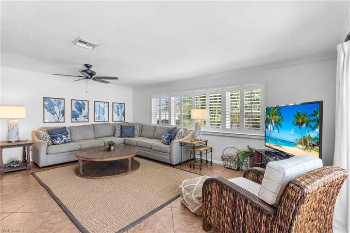 Living room with light tile patterned flooring, crown molding, and ceiling fan