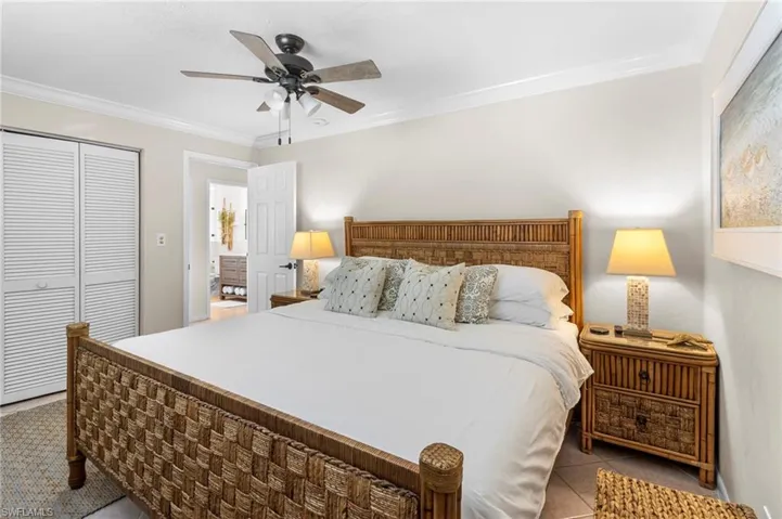 Bedroom with tile patterned floors, crown molding, a closet, and ceiling fan