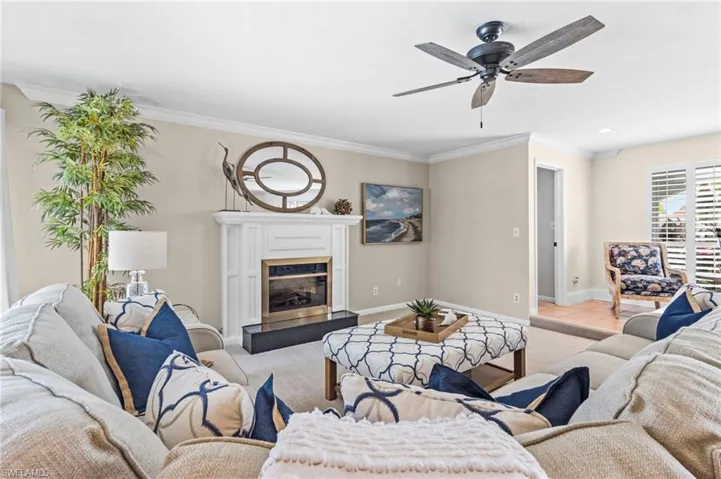 Tiled living room with a tiled fireplace, crown molding, and ceiling fan