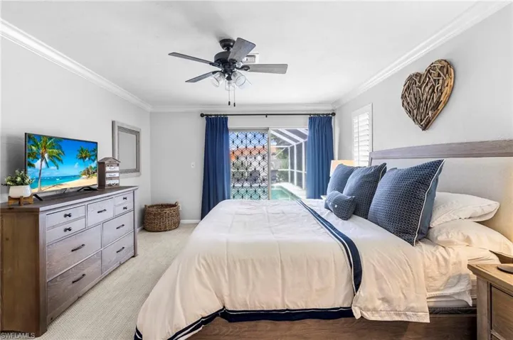 Carpeted bedroom featuring crown molding and ceiling fan