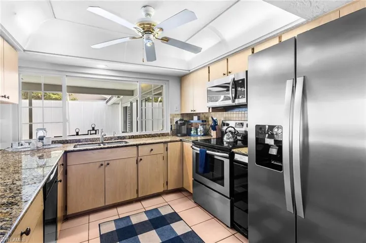 Kitchen featuring tasteful backsplash, stainless steel appliances, sink, ceiling fan, and a raised ceiling