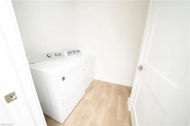 Clothes washing area featuring separate washer and dryer and light hardwood / wood-style floors