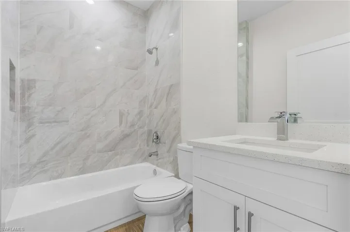 Full bathroom with tiled shower / bath combo, vanity, and toilet