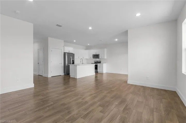 Unfurnished living room featuring hardwood / wood-style floors and sink