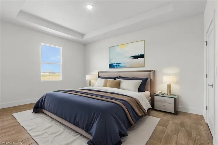 Bedroom with light hardwood / wood-style flooring and a raised ceiling