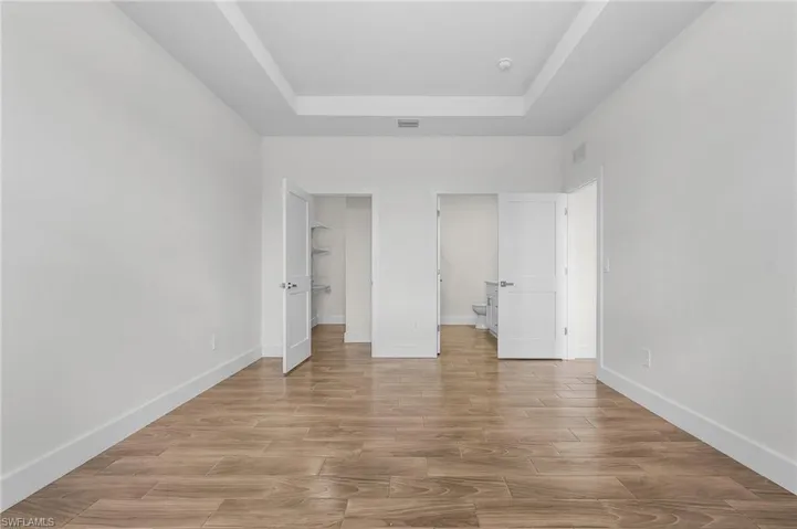 Unfurnished bedroom featuring light hardwood / wood-style floors and a tray ceiling