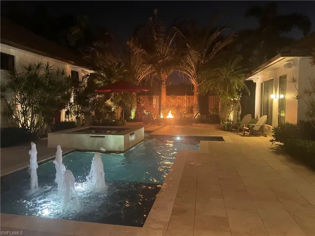 Courtyard at night with water feature and firepit.