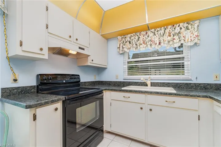 Kitchen with electric range, dark countertops, and under cabinet range hood