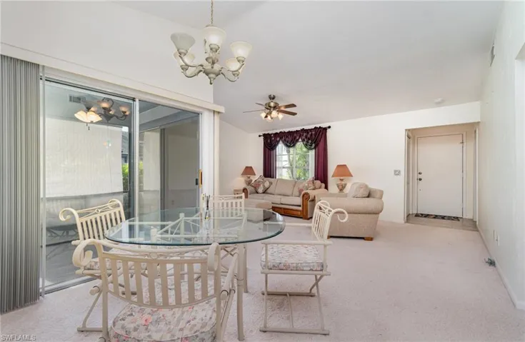 Carpeted dining area featuring a chandelier and a ceiling fan