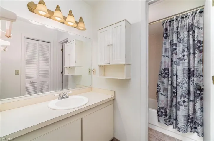 Full bathroom featuring shower / bath combo with shower curtain, vanity, and a closet