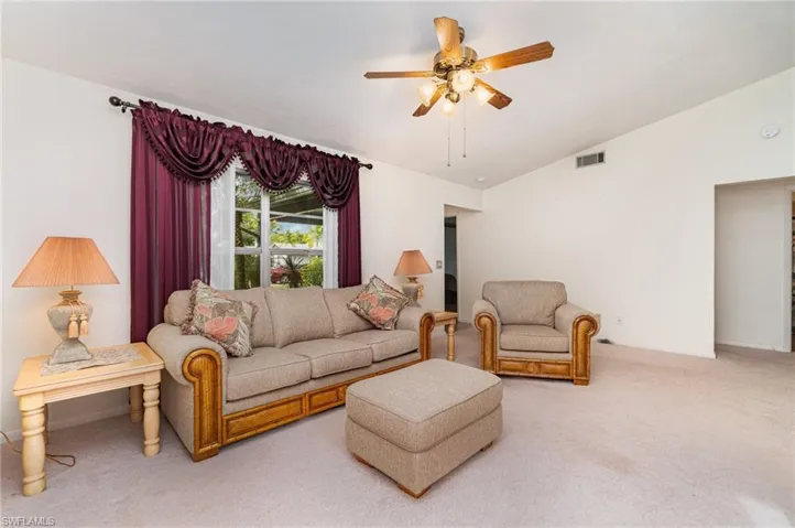 Living area with vaulted ceiling, carpet, and ceiling fan