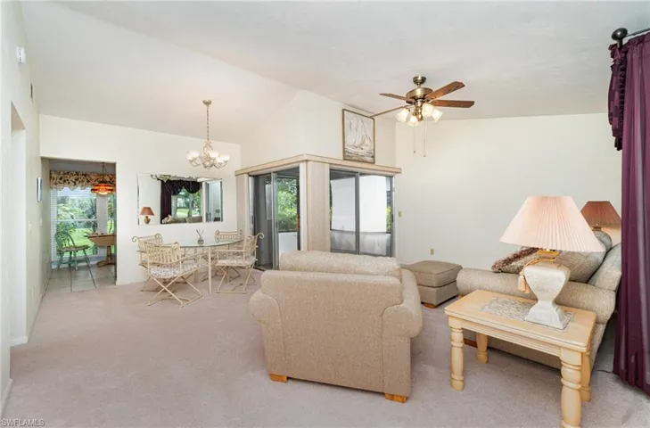 Carpeted living room featuring lofted ceiling, plenty of natural light, ceiling fan, and a chandelier